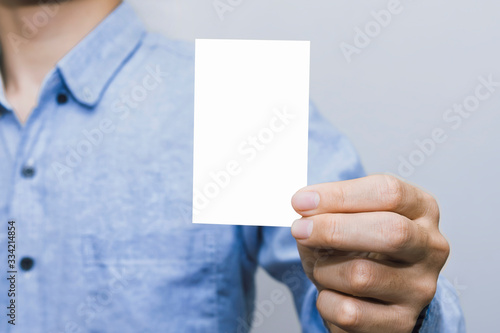 Person holding a white business card on a white background, vertical, template, blue shirt, business man.