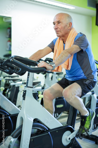Uomo anziano  si allena in una palestra con lo spinning