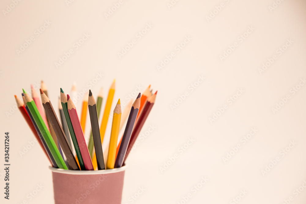 Colored pencils in a paper pencil holder with uniform white background