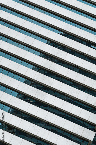 Modern glass and concrete facade of office building with reflections of sky