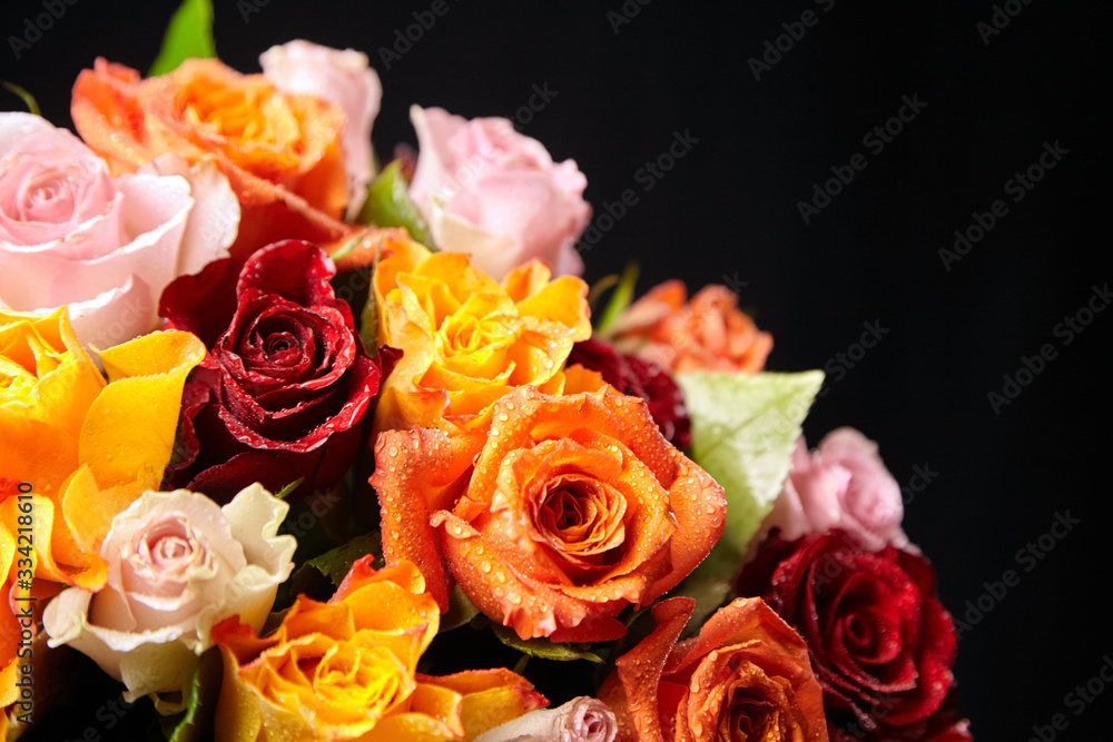 Bouquet of different color roses with water drops on petals on a black background. Red, orange and pink flowers. Romantic Valentine's Day Gift