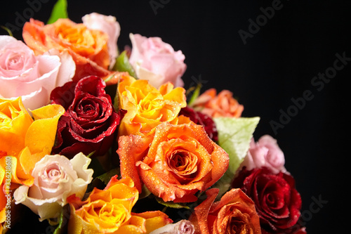 Bouquet of different color roses with water drops on petals on a black background. Red  orange and pink flowers. Romantic Valentine s Day Gift