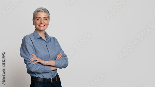 Portrait Of Mature Businesswoman Posing With Folded Arms Over Light Background photo