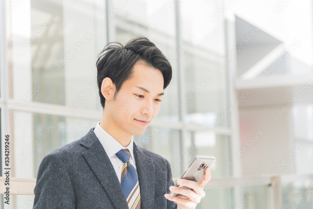 Obraz premium スマートフォンを手に持つビジネスマン