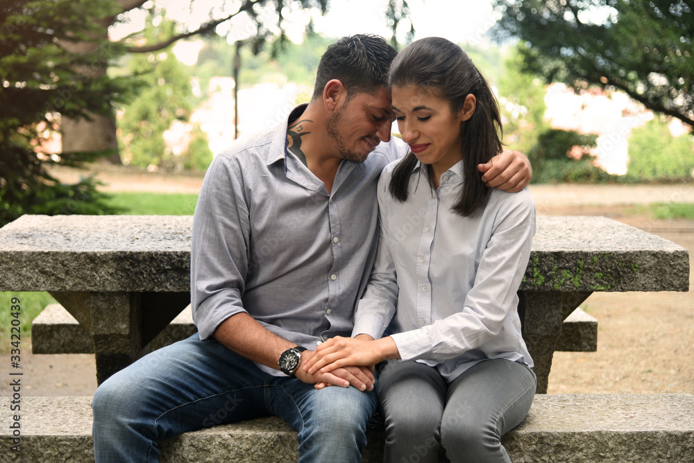 Cute young couple cuddling on a bench