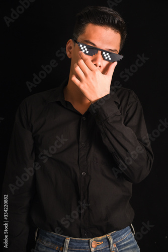 Handsome young man in black shirt keeping arms crossed wear glasses on black background , Asia Portrait