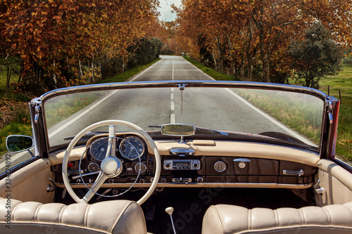 Interior of vintage car on the tar road in autumn. Trees on the side. Car stopped