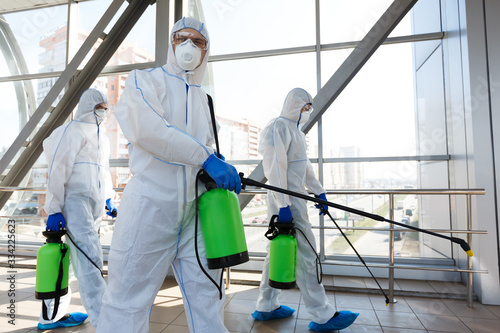 Professional workers in hazmat suits disinfecting indoor accommodation photo