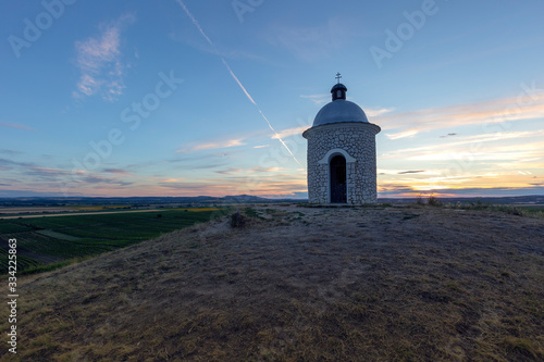 Stone chapel Hradistek at sunset with beautiful blue sky in the foreground green grass with pink flowers