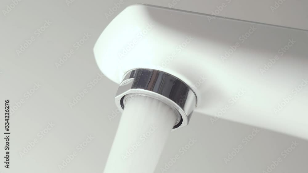 Water flow from the open modern white tap in the bathroom. Modern faucet with running water. Bathroom Interior. Hotel Bathroom. Interior decoration. Water supply Water flow from the open modern white tap in the bathroom. Modern faucet with running water. Bathroom Interior. Hotel Bathroom. Interior decoration. Water supply