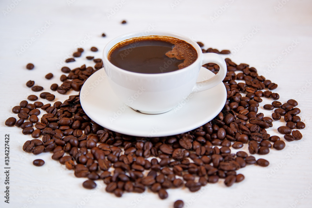 White cup of coffee stands on coffee beans White cup of coffee stands on coffee beans