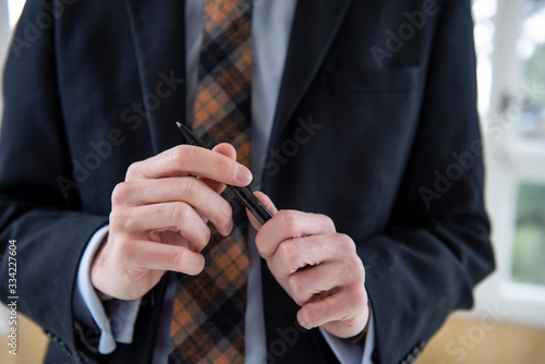 close up of the hands of a man holding a pen