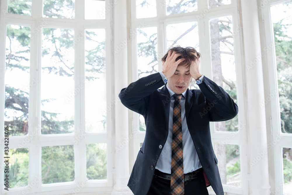 man in a suit touching his head in despair man in a suit touching his head in despair