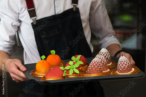 The waiter advertises cakes in the form of fruits, berries and cones
