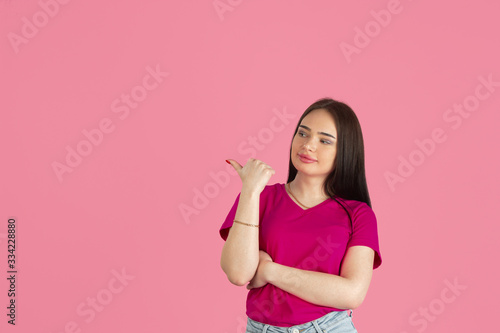 Pointing. Monochrome portrait of young caucasian brunette woman isolated on pink studio background. Beautiful female model in shirt. Human emotions  facial expression  sales  ad concept. Youth culture