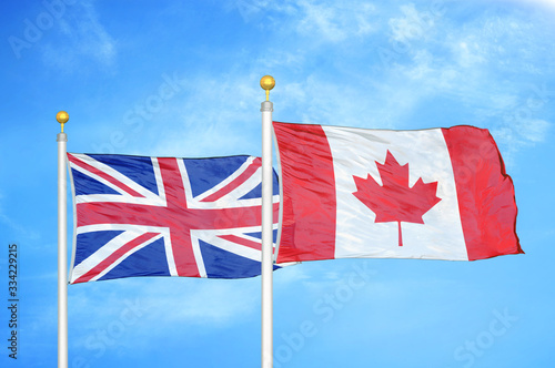 United Kingdom and Canada two flags on flagpoles and blue cloudy sky photo