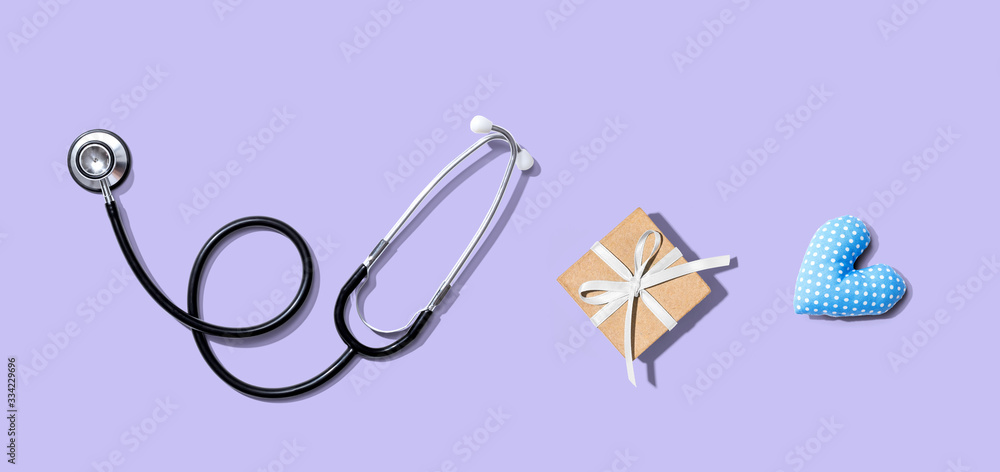 Obraz premium Stethoscope with a gift and a heart cushion - flat lay