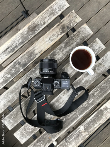 Travel camera and coffee cup on wooden table