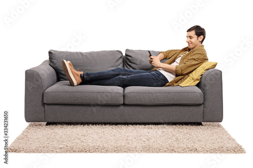 Young man resting on a sofa and looking at a mobile phone