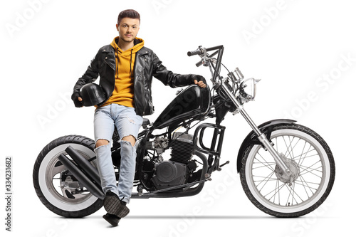Guy biker holding a helmet and sitting on a custom motorbike