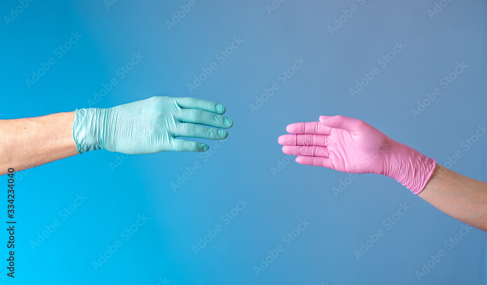 Two hands in rubber medical gloves. Man in mint and woman in pink. Protection, isolation and distance during pandemic