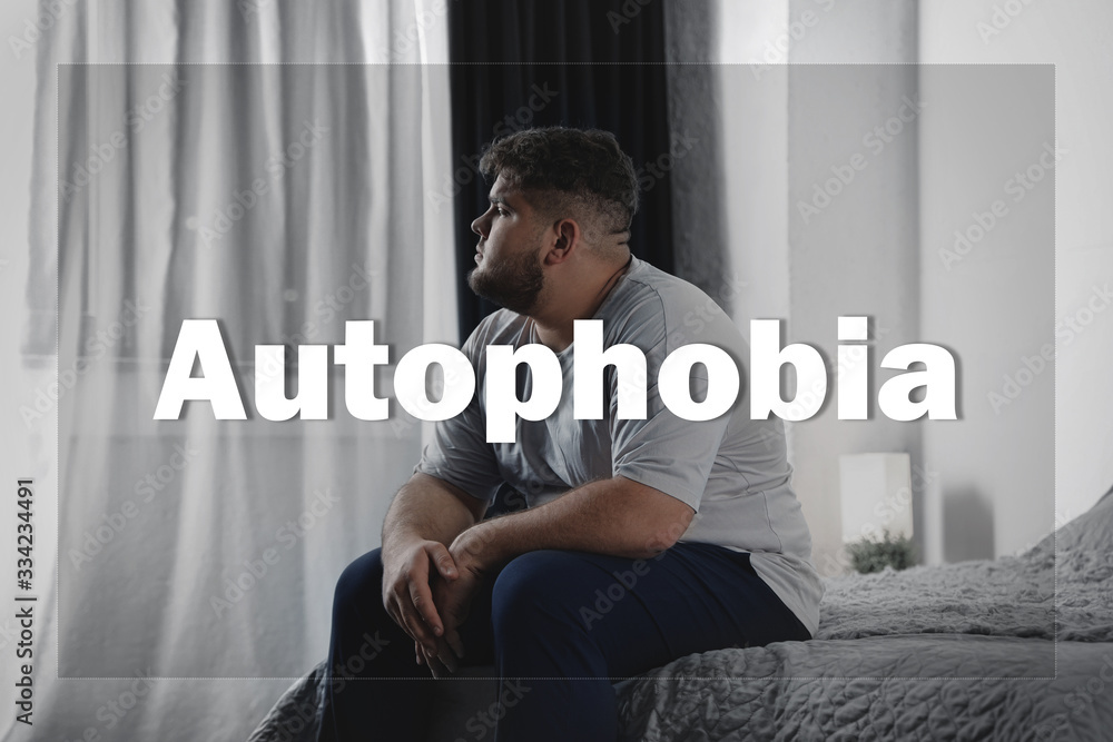 Depressed overweight man sitting alone on bed at home. Autophobia - obrazy, fototapety, plakaty 