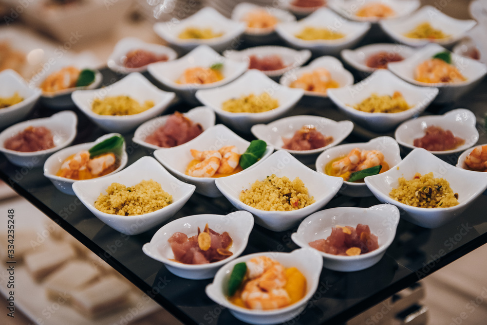 snacks in small ceramic bowls on the buffet table, there are couscous, shrimp, meat snacks in small ceramic bowls on the buffet table, there are couscous, shrimp, meat