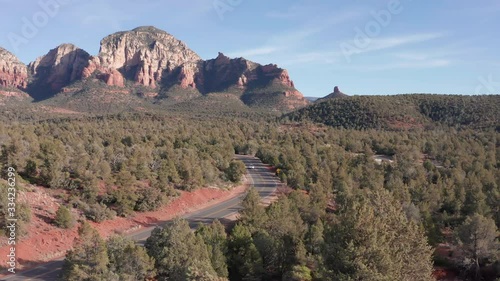 AERIAL: Shot in Sedona Arizona of a car driving through rock formations and a beautiful landscape on a sunny day photo