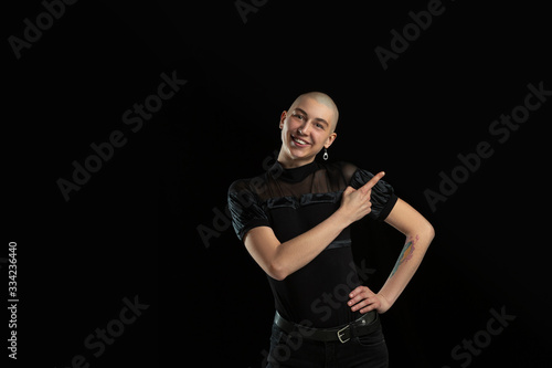 Showing something. Monochrome portrait of young caucasian bald woman isolated on black studio background. Beautiful female model. Human emotions, facial expression, sales, ad concept. Youth culture.