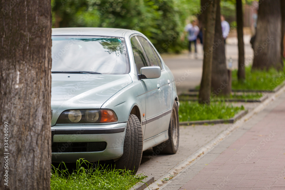 Car parked in pedestrian zone under trees along street with walking people on summer day. Car parked in pedestrian zone under trees along street with walking people on summer day.