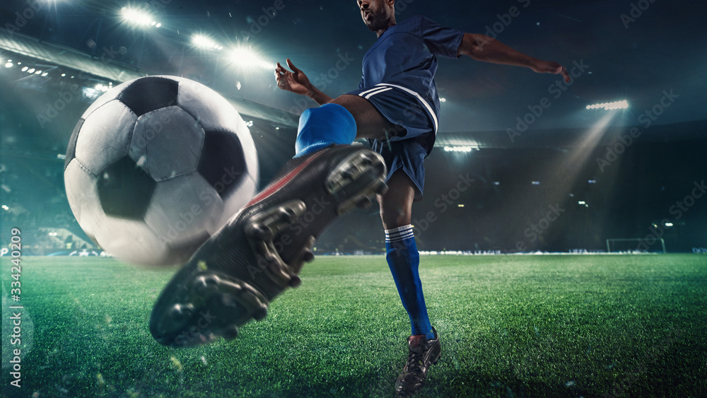 Professional football or soccer player in action on stadium with flashlights, kicking ball for winning goal, wide angle. Concept of sport, competition, motion, overcoming. Field presence effect. - obrazy, fototapety, plakaty 