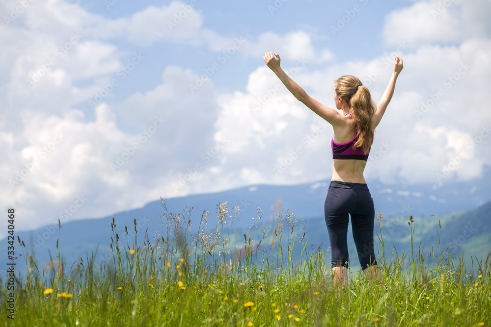Slim young woman with raised arms outdoors on background of beautiful mountain landscape on sunny summer day. Slim young woman with raised arms outdoors on background of beautiful mountain landscape on sunny summer day.