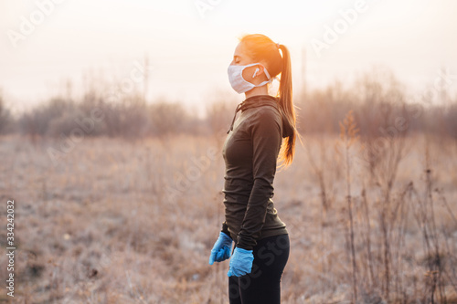 COVID-19 Pandemic Coronavirus girl in mask and blue gloves during quarantine went out to run photo