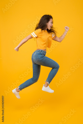 Run hard to arrive at goal. Dynamic woman run yellow background. Sexy girl jump with long run. Energetic look of fashion model. Casual style. Active lifestyle. Run and become