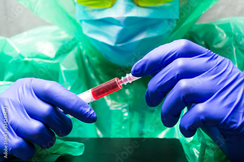 Hand of a doctor, researcher or scientist in a blue glove holds a vaccine