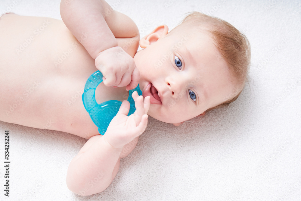 The baby s teeth are being cut. A cute kid with blue eyes nibbles a toy. The baby s teeth are being cut. A cute kid with blue eyes nibbles a toy.