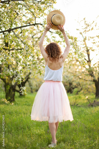 Young attractive woman with curly hair walking in a green flowered garden. Spring mood photo