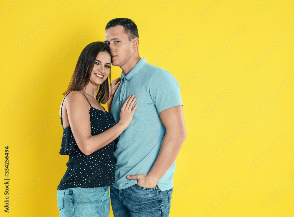 Naklejka premium Happy young couple hugging on yellow background. Space for text