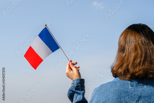 Fotografie, Obraz Woman hand with French swaying flag on the blue sky