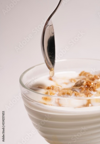 Homemade breakfast of milk, jelly and honey. Spoon over a transparent glass on a white background