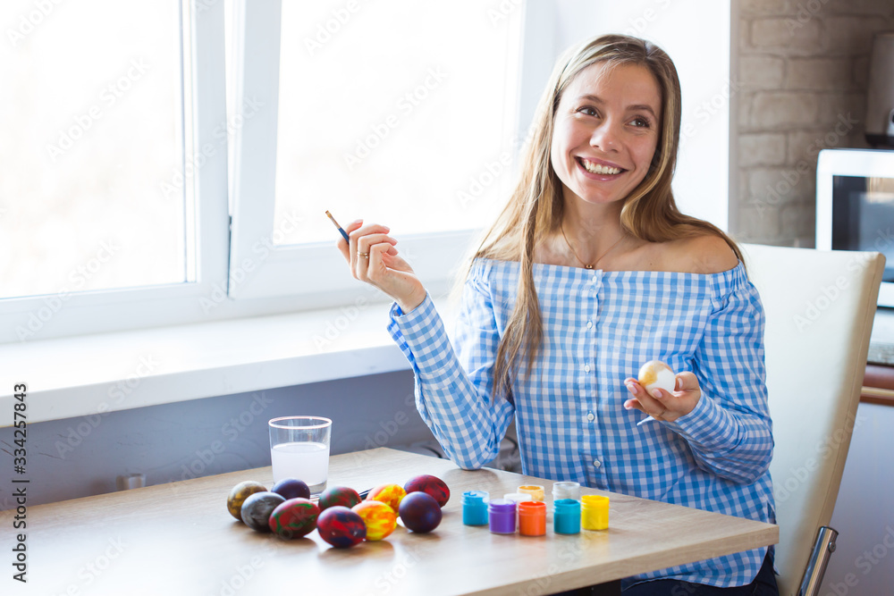 Holidays, handmade and creation concept - Happy young woman draws on Easter egg. Holidays, handmade and creation concept - Happy young woman draws on Easter egg.