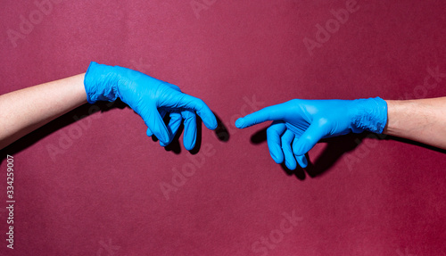 Two hands in medical gloves as a creation of Michelangelo Adam.