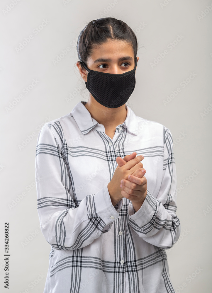 A teenage girl with protective mask on face using sanitizer to clean her hands A teenage girl with protective mask on face using sanitizer to clean her hands