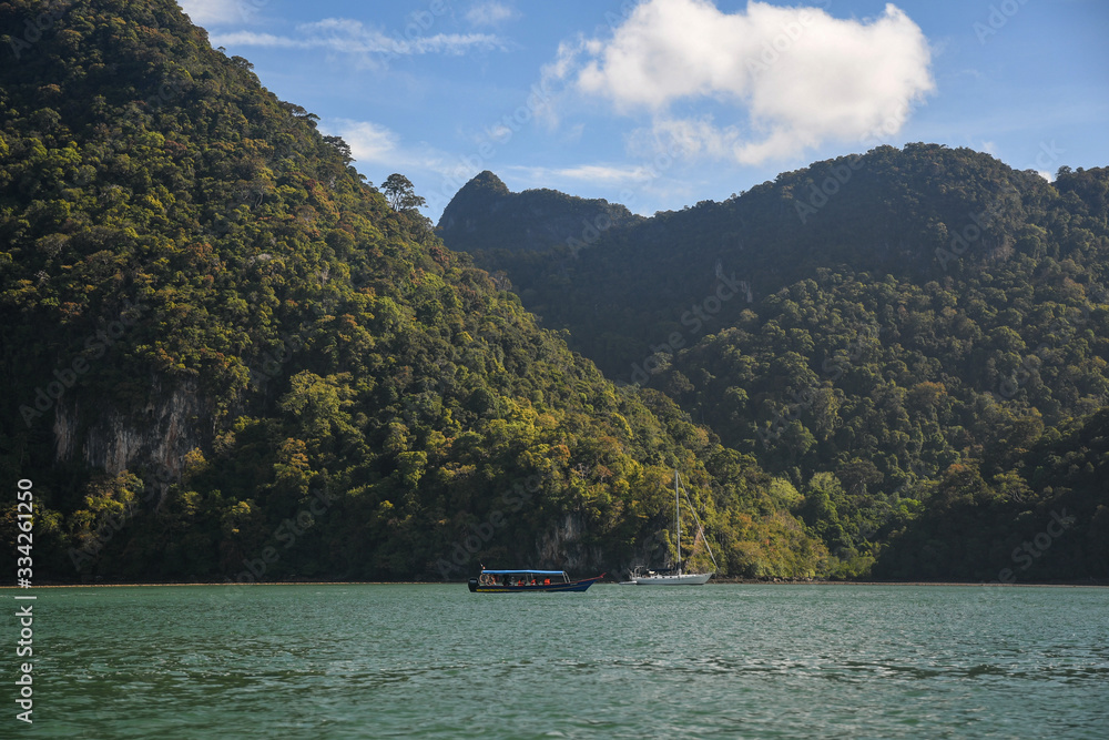 Fototapeta premium Island Hopping in Langkawi. Familly vacation and tours in Malaysia. Scenic views of small green rocky islands from the boat on Andaman Sea.