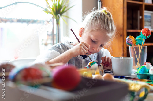 Canvas Print Portrait of adorable blonde girl at home painting easter eggs