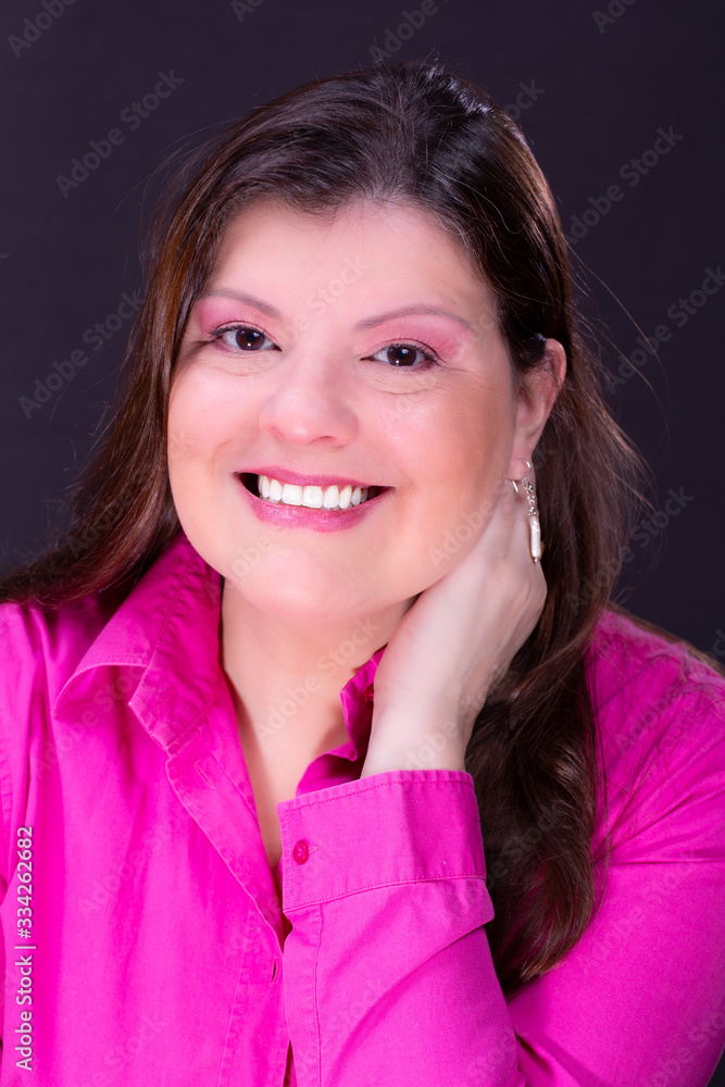 Lady headshot portrait. She is in her 40s, has long smooth black hair. She is wearing a casual fuchsia shirt. She is smiling, holding a hand to the side of her face and looking to the camera. Lady headshot portrait. She is in her 40s, has long smooth black hair. She is wearing a casual fuchsia shirt. She is smiling, holding a hand to the side of her face and looking to the camera.