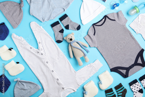 Flat lay composition with child's clothes and toy bear on light blue background