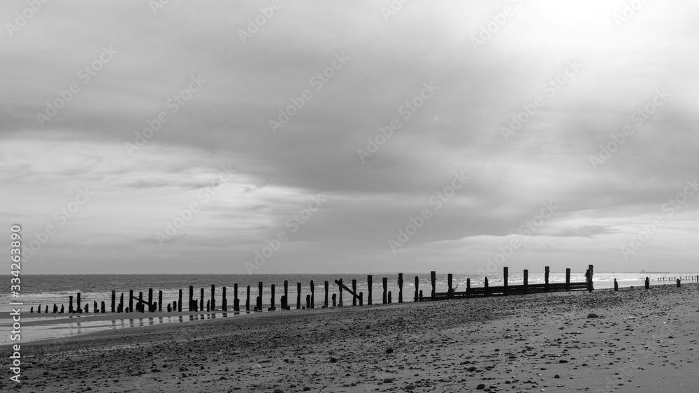 A moody black and white beach with a cloudy sky above
