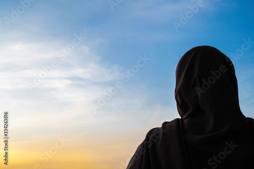 Silhouette of muslim woman in scarf at sunset. America. Concept
