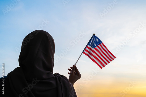 Foto Silhouette of muslim woman in scarf with American, flag of at sunset